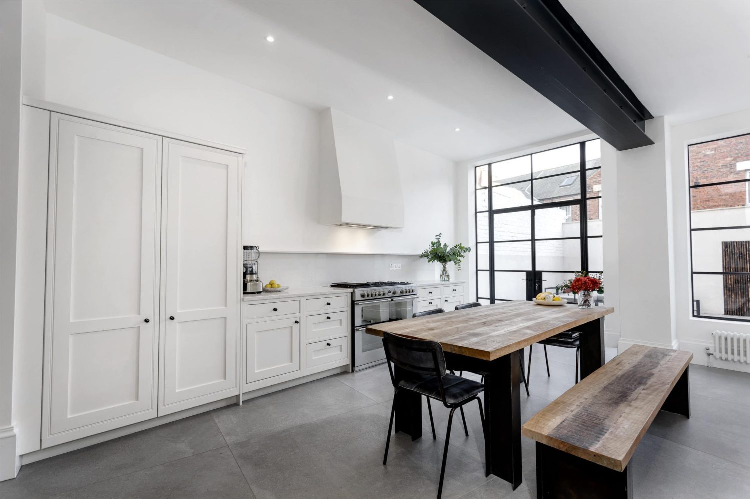 White kitchen with wooden dining table and bench in the centre