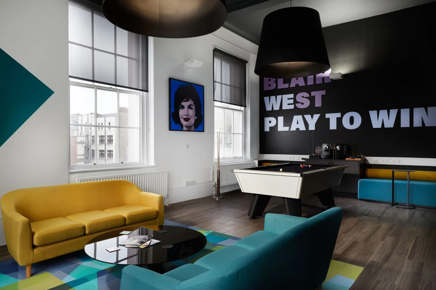 Brightly coloured office recreational area with pool table and yellow and blue sofas