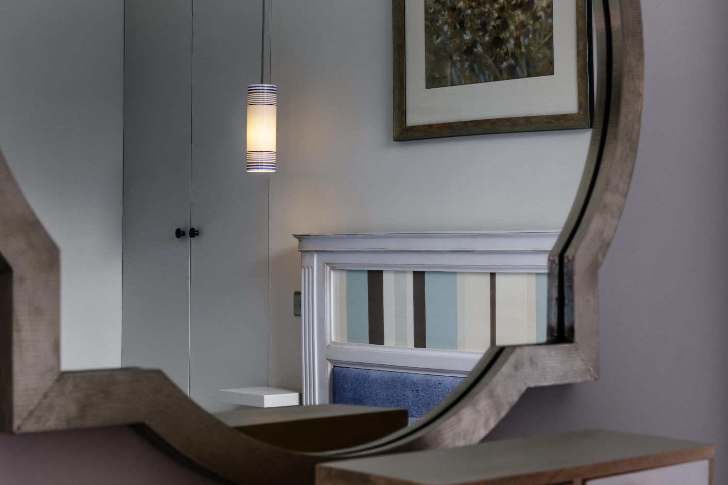 View in bedroom mirror of pendant light hanging beside bed