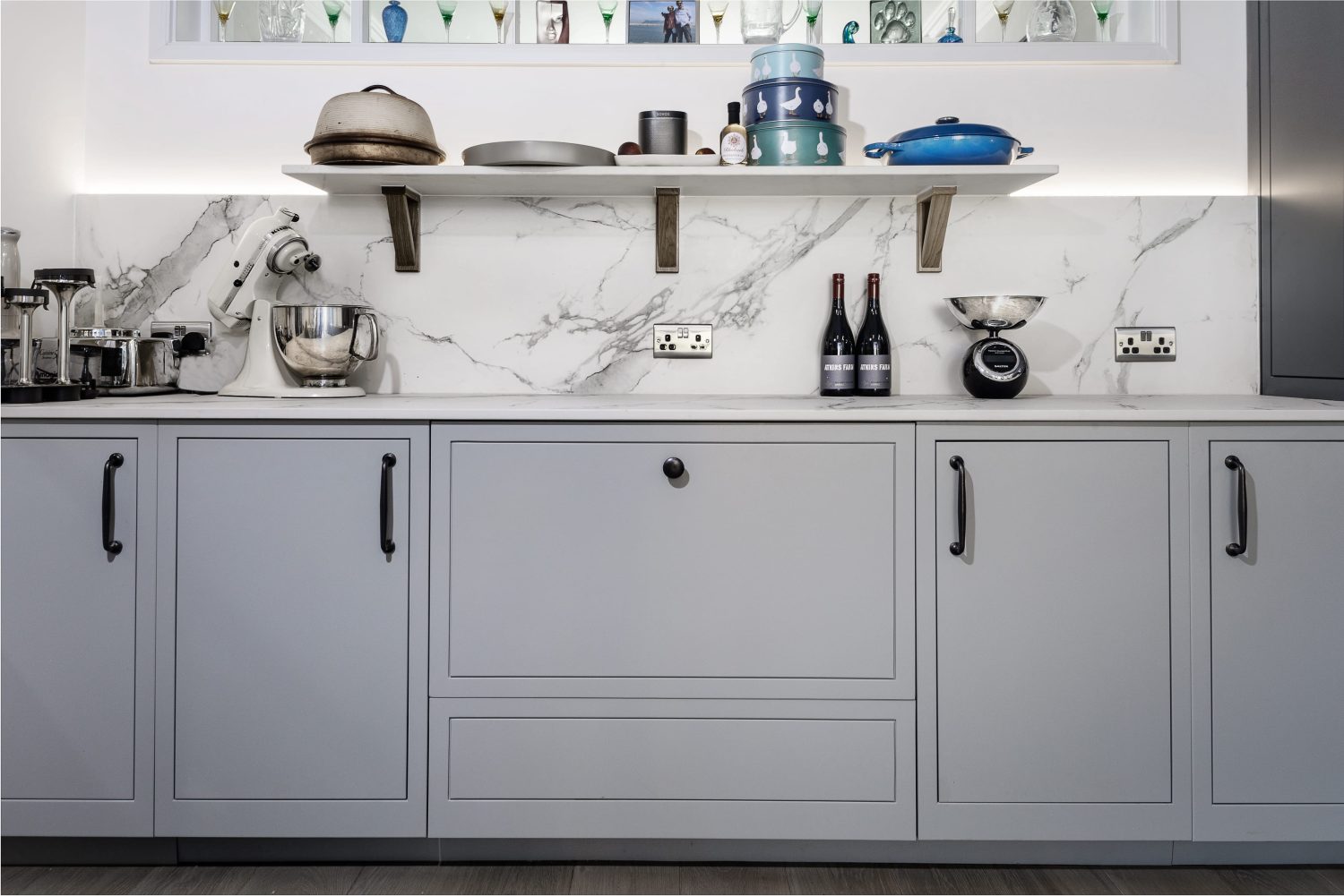 White marble kitchen counter and back splash with grey cabinetry and cooking equipment