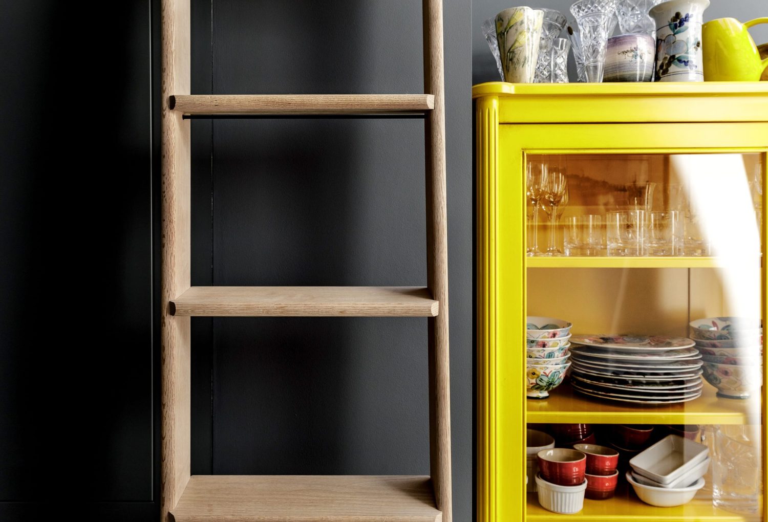 Wooden ladder against dark blue wall next to yellow cabinet