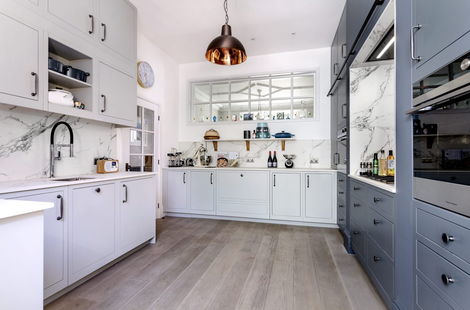 Kitchen with light and dark cabinetry and copper pendant light