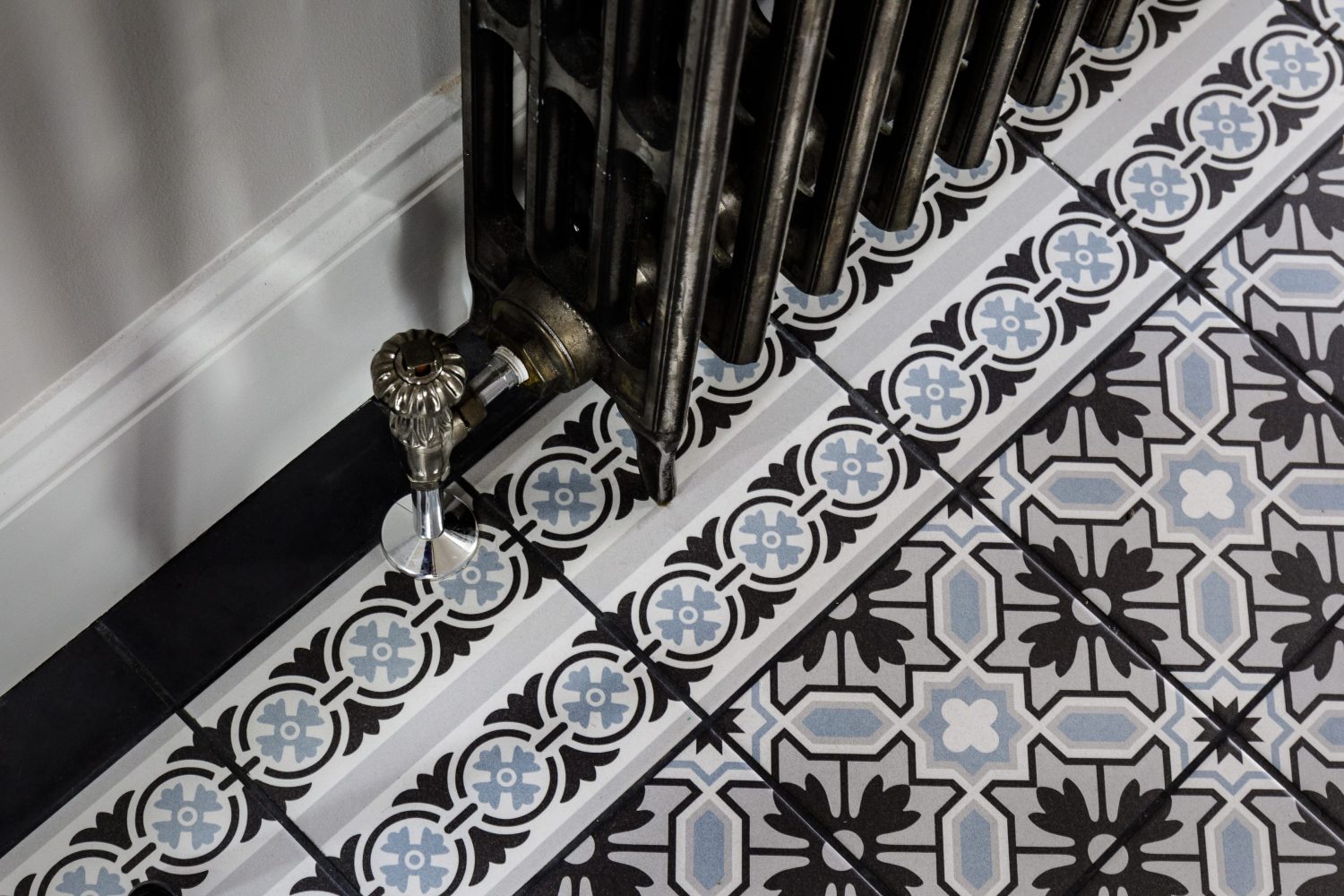 Blue and grey patterned floor tiles with dark grey metal radiator