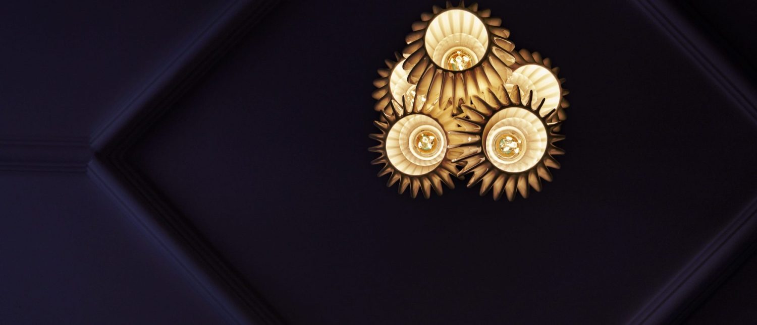 Gold spiked lampshade with multiple lightbulbs against dark blue ceiling