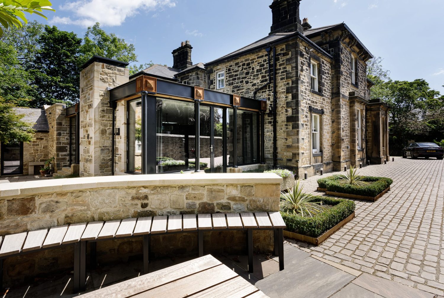 Exterior side of stone built house with windows with black framing and copper accents