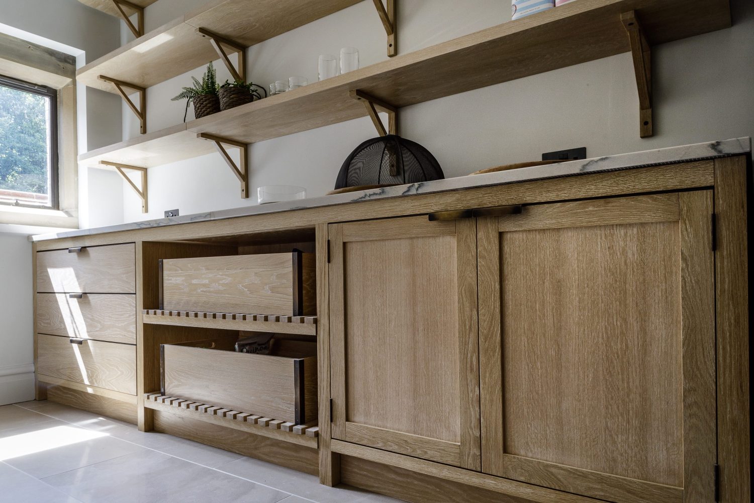 Wooden cabinets with white marble countertop and wooden shelves along wall above