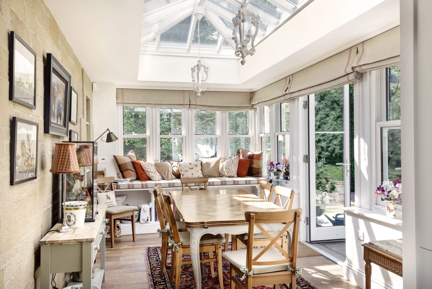 Cottage conservatory extension with dining table and window seat in beige traditional interior