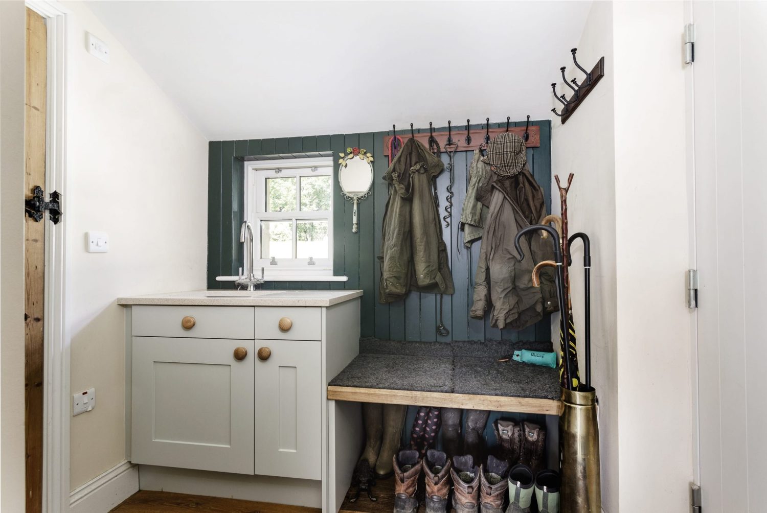 Small sink beside coat rack with shoe storage beneath