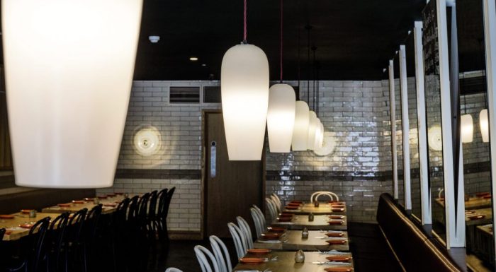 White pendant lights hanging in a row above restaurant seating area