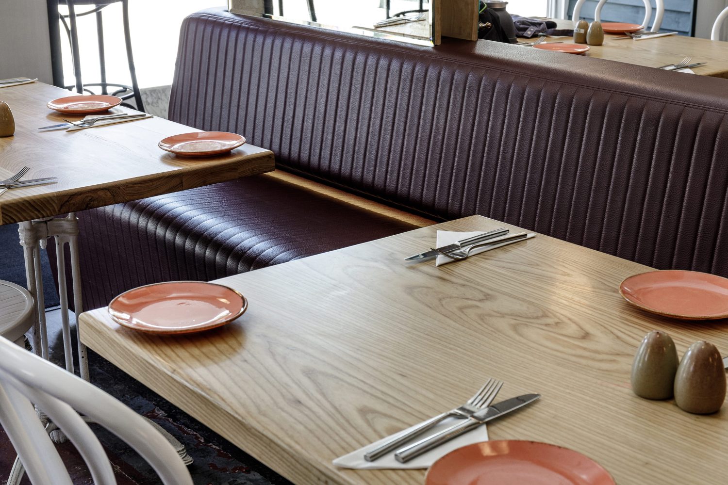 Restaurant booth seating behind wooden tables with orange plates
