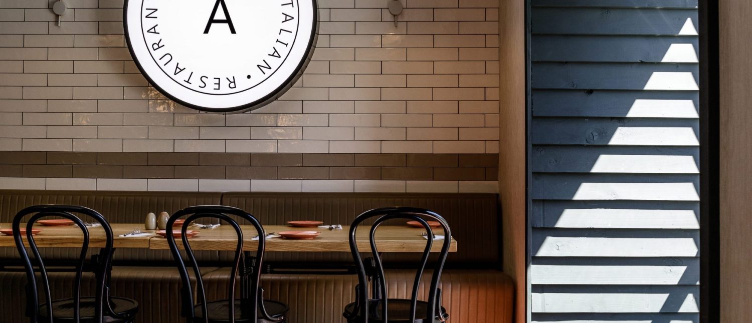 Restaurant sign above seating area with sunlight through window