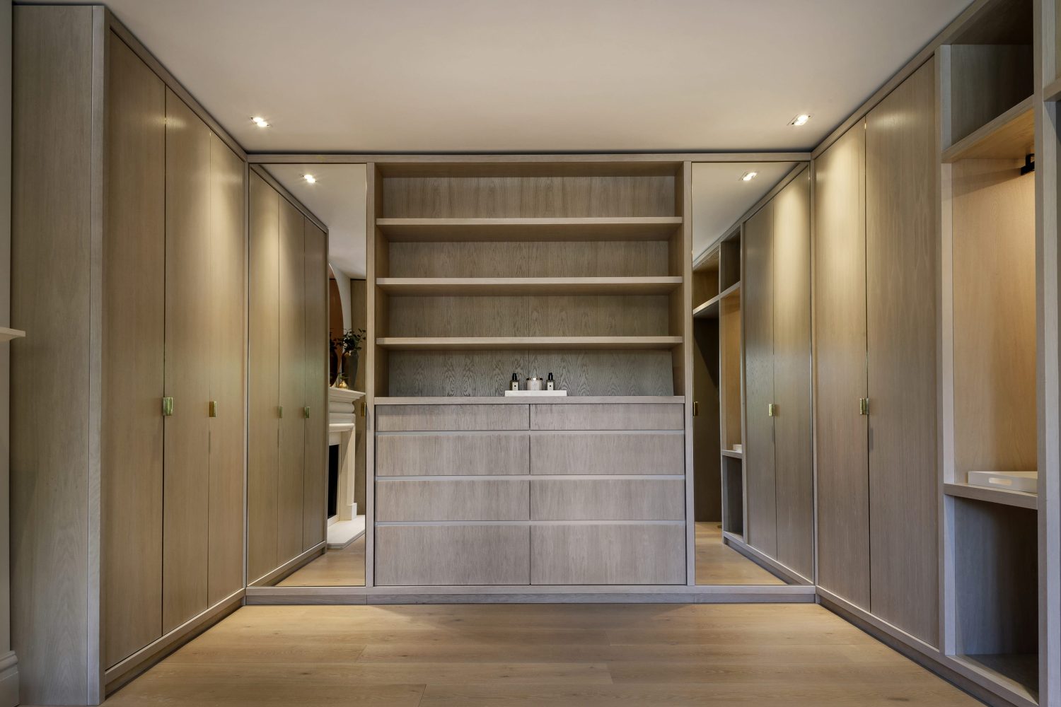 Dressing room with wooden wardrobes and vertical mirrors on either side of wooden shelving unit