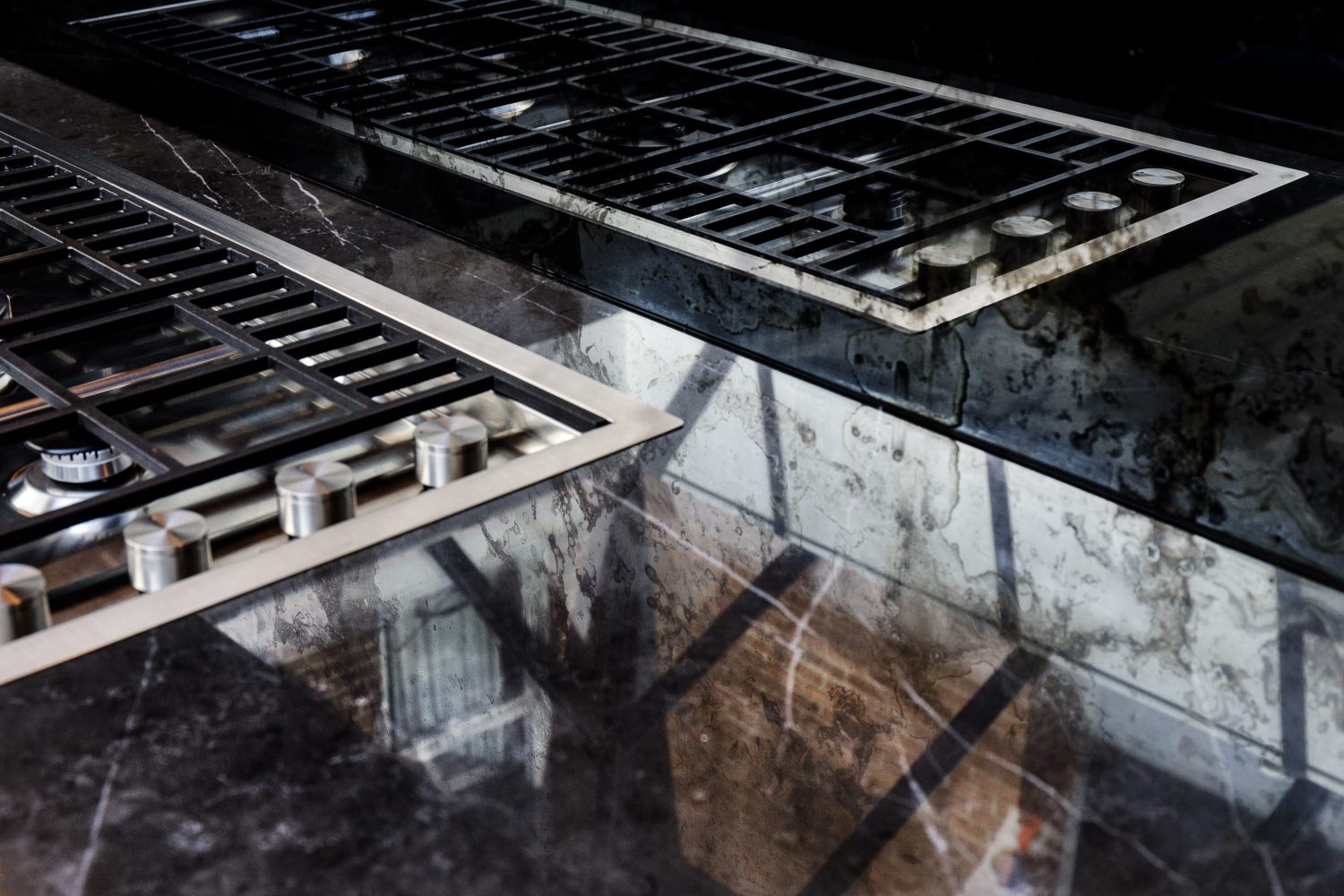Dark marble kitchen counter around the corner of a stove with an antiqued mirror backsplash