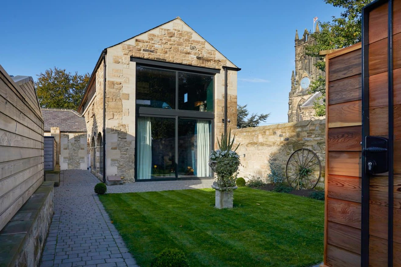 Exterior side of barn conversion with stone walls and large windows