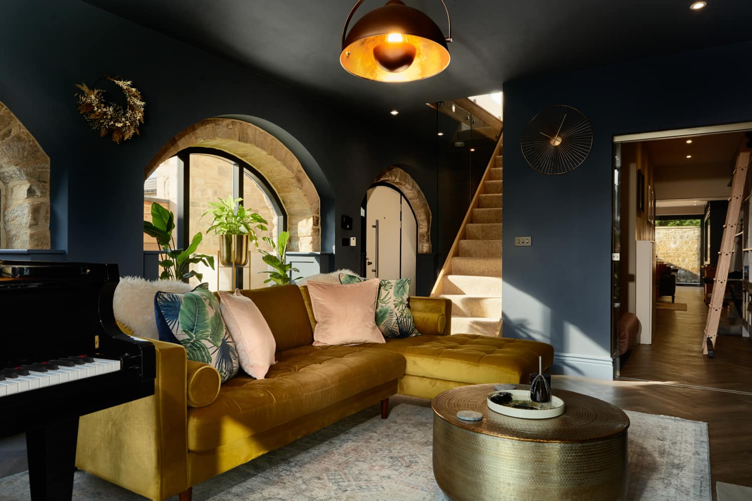 Living room with golden yellow sofa and arched windows in dark blue walls