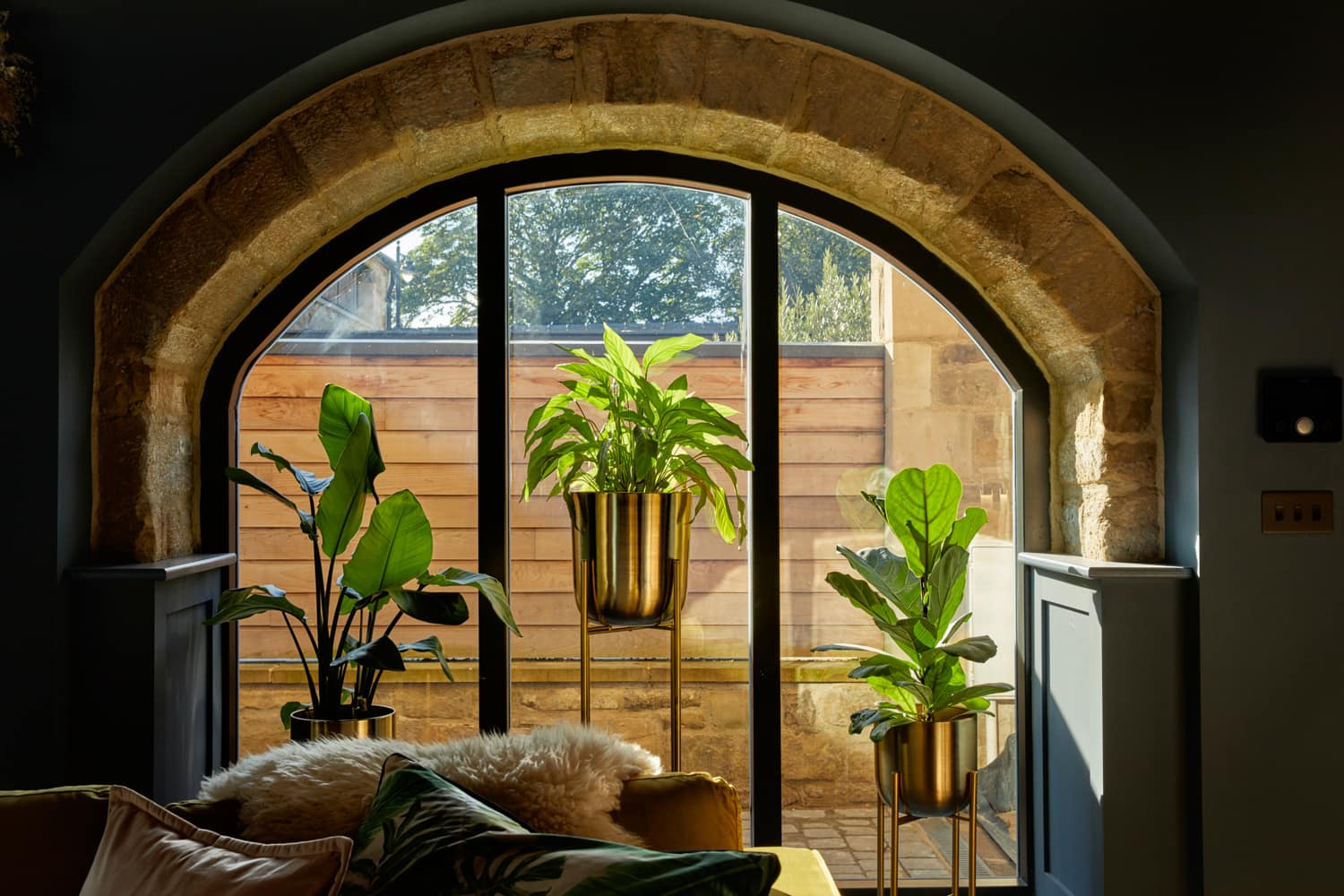 Large arched window with stone border and plants in front