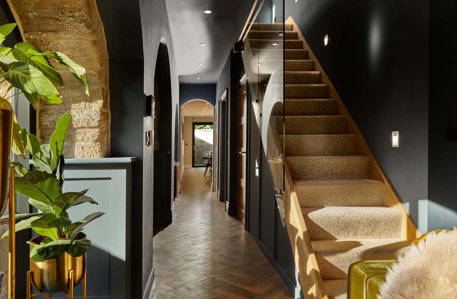 Hallway with arched doorway at end and carpeted staircase beside