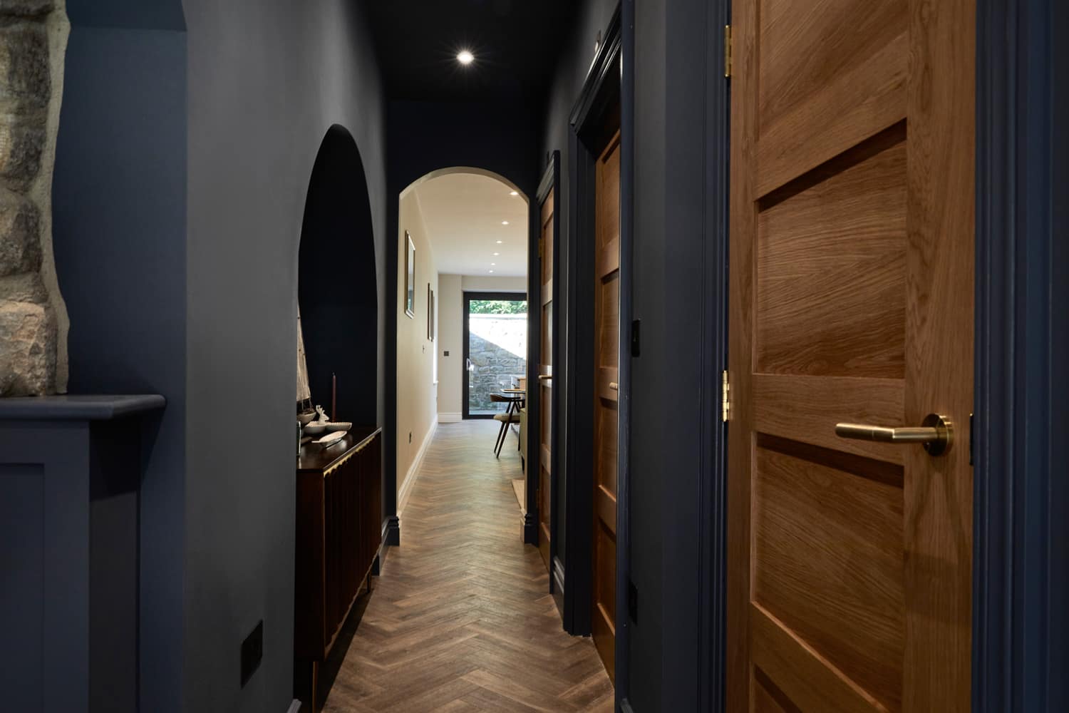 Hallway with dark blue walls and wooden doors leading to arched doorway