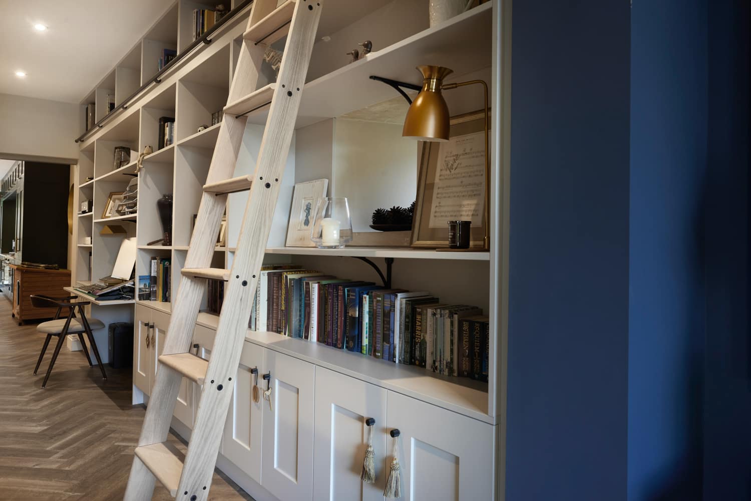 Sliding ladder across white shelving unit filled with books and decoration