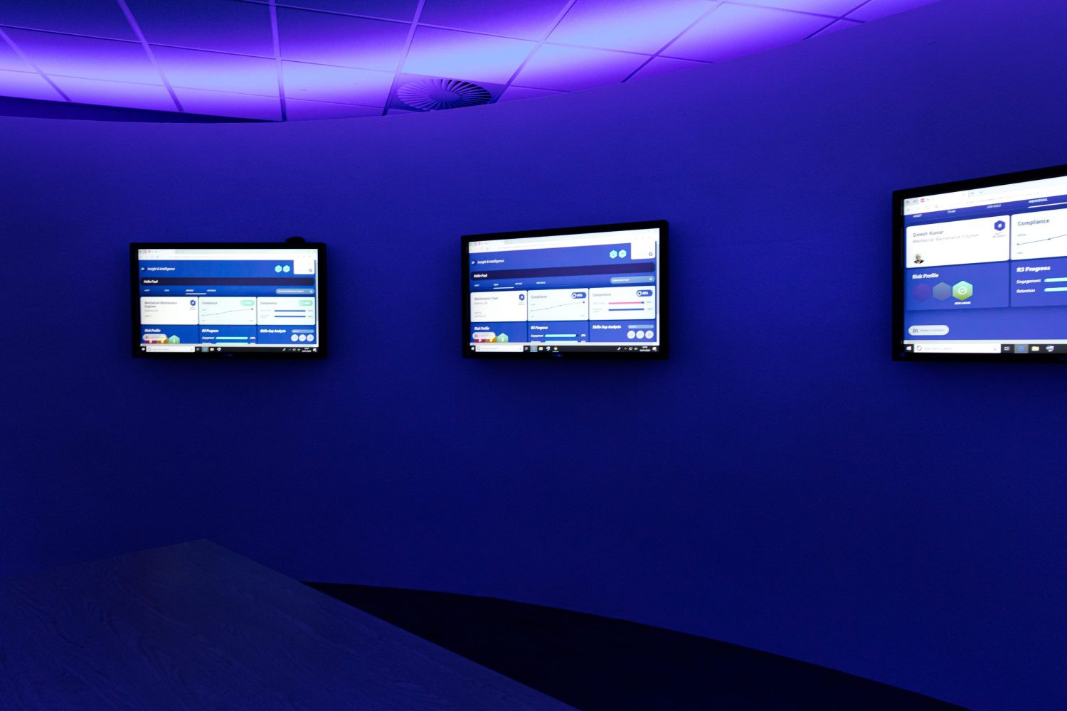 TVs mounted on a curved wall with purple LEDs glowing above