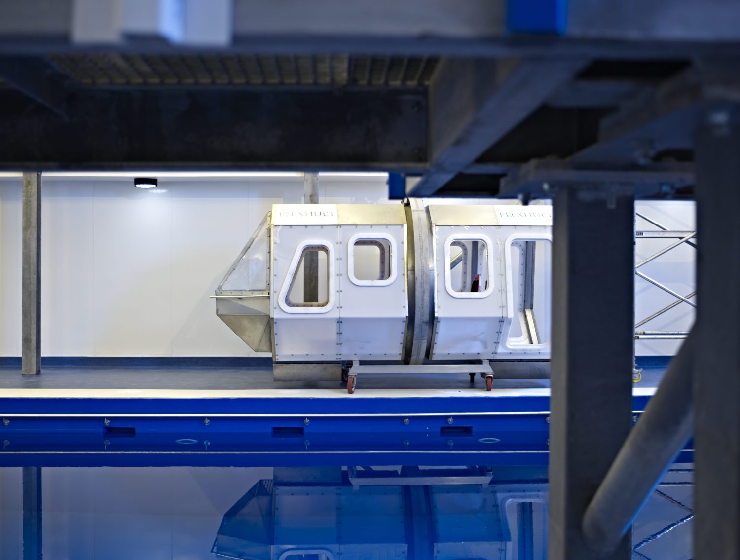 Large metal container with windows on edge of blue pool below