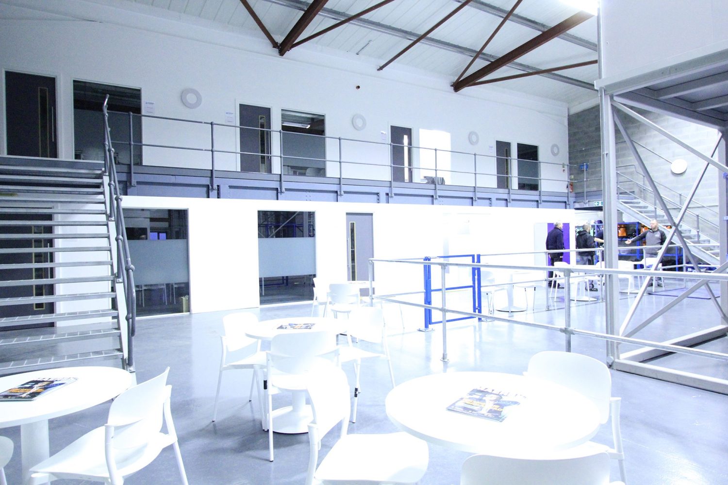 Seating area with white tables and chairs and stairs to either side leading to a raised floor and doors leading to other rooms