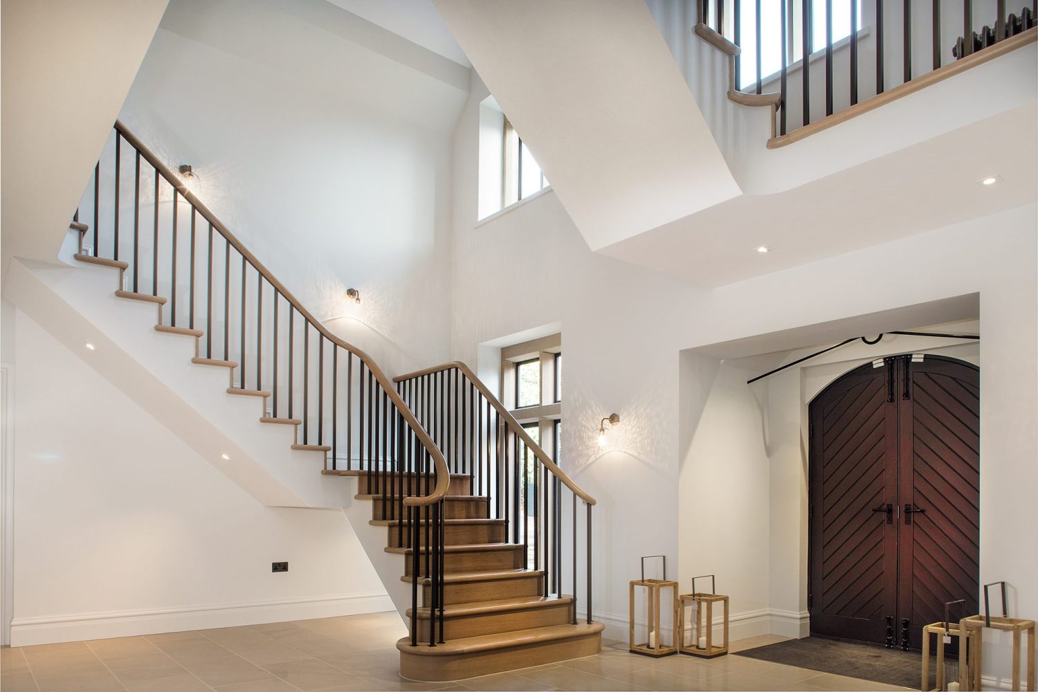 Bottom of a staircase in a large house with white walls and wooden double door
