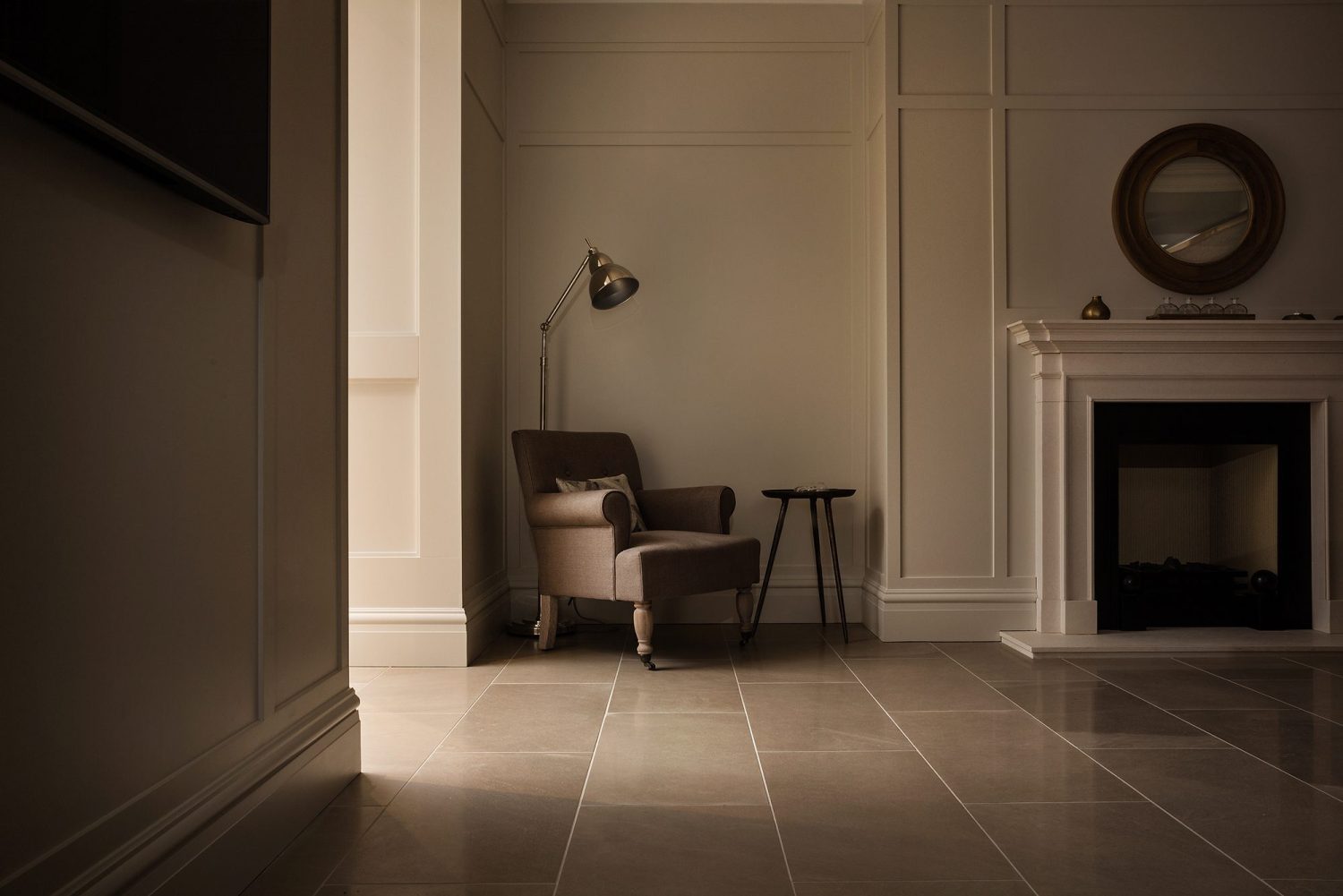 Shadowed chair in a corner with large lamp beside