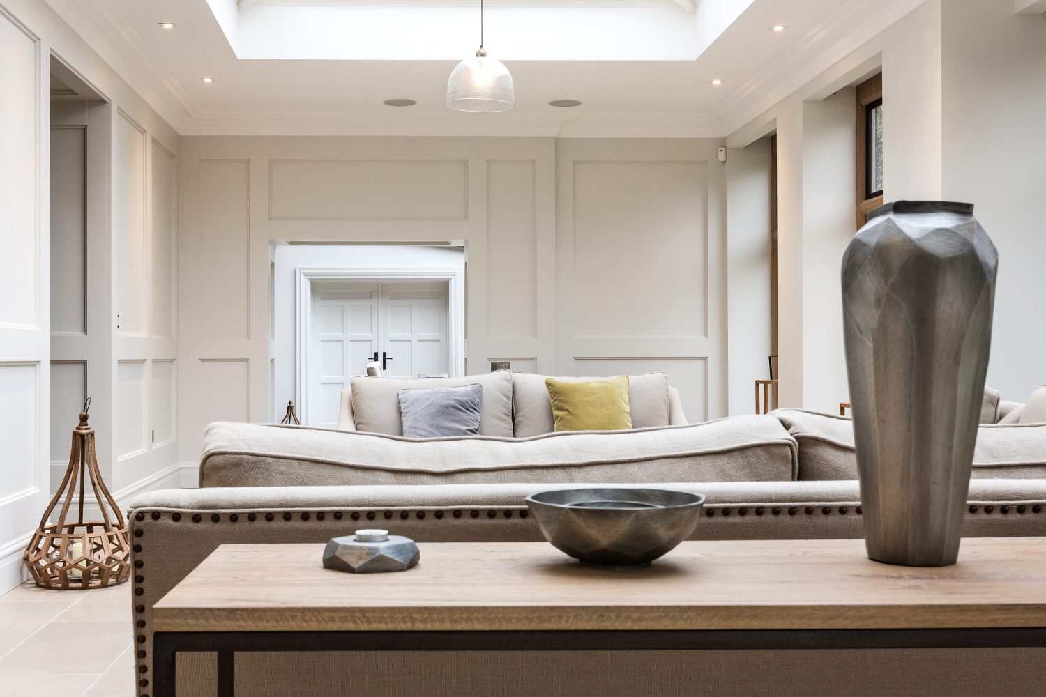 Side table with grey metal vases and beige sofas behind