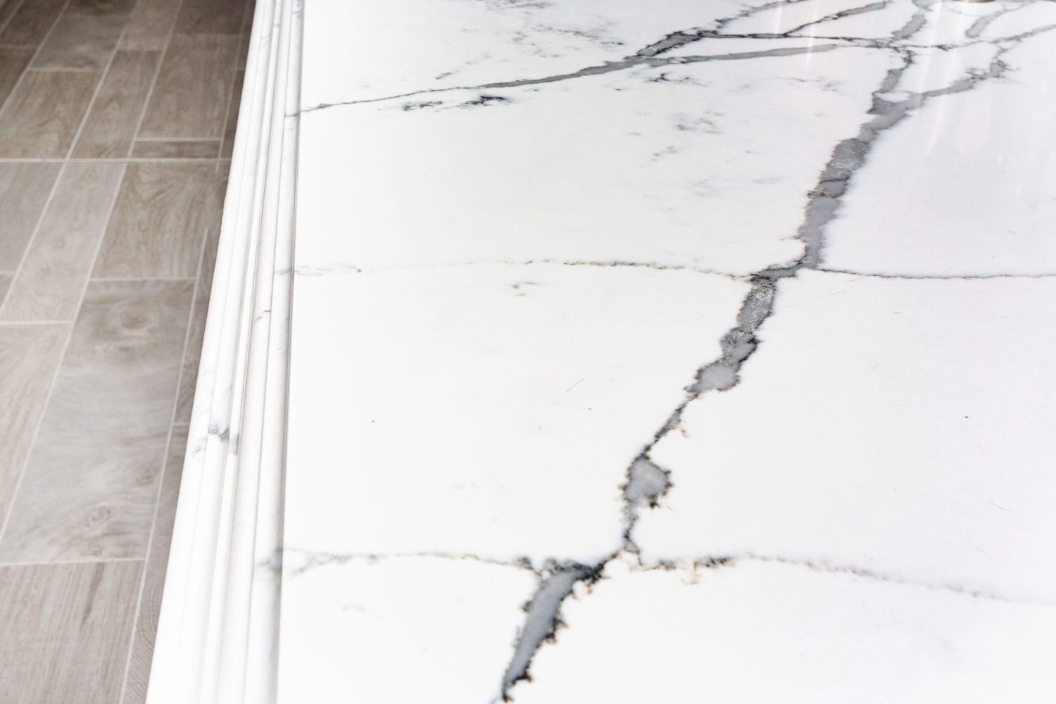 Close up white marble countertop with wooden flooring to the left