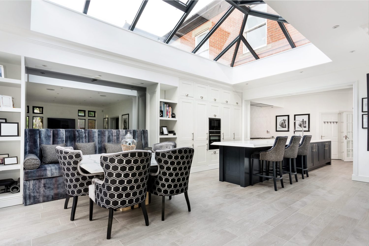 Kitchen and dining area with glazed ceiling and dark grey seating around white marble table