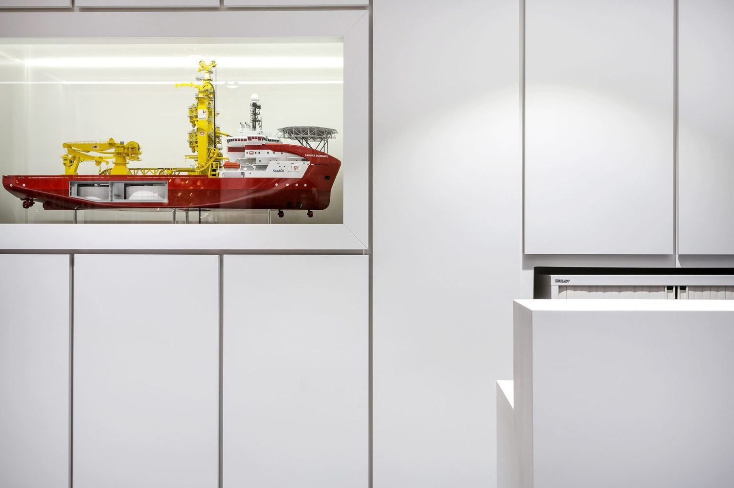 White panelled wall with large model ship encased within wall behind a screen