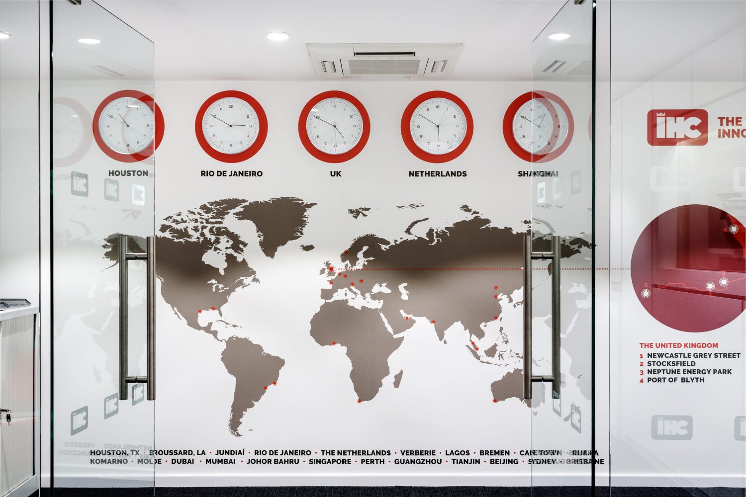 Glass doors leading to wall with clocks showing different time zones and a large map graphic below