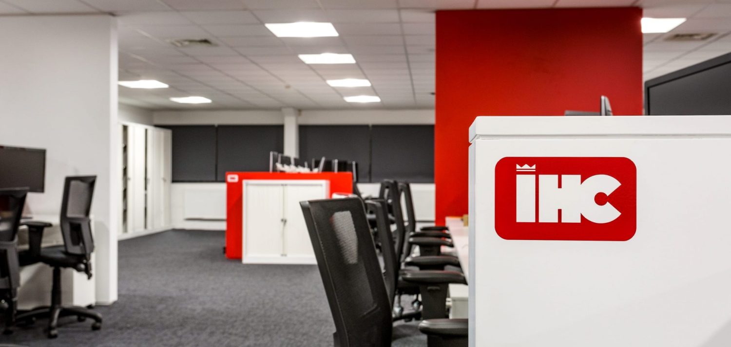Office area with red partition walls and company logo beside desk