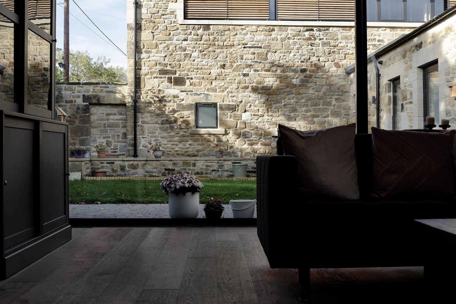 Large window with potted flowers in garden outside and sofa in front of window