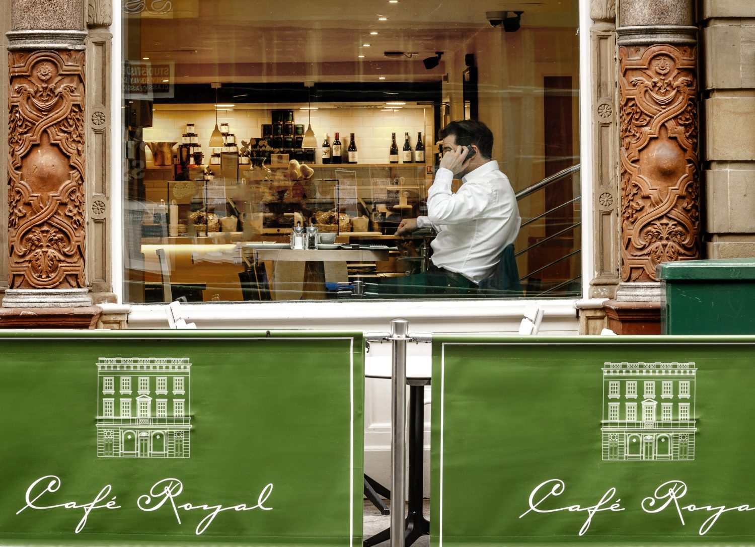 Exterior of building with green Cafe Royal banners below a large window