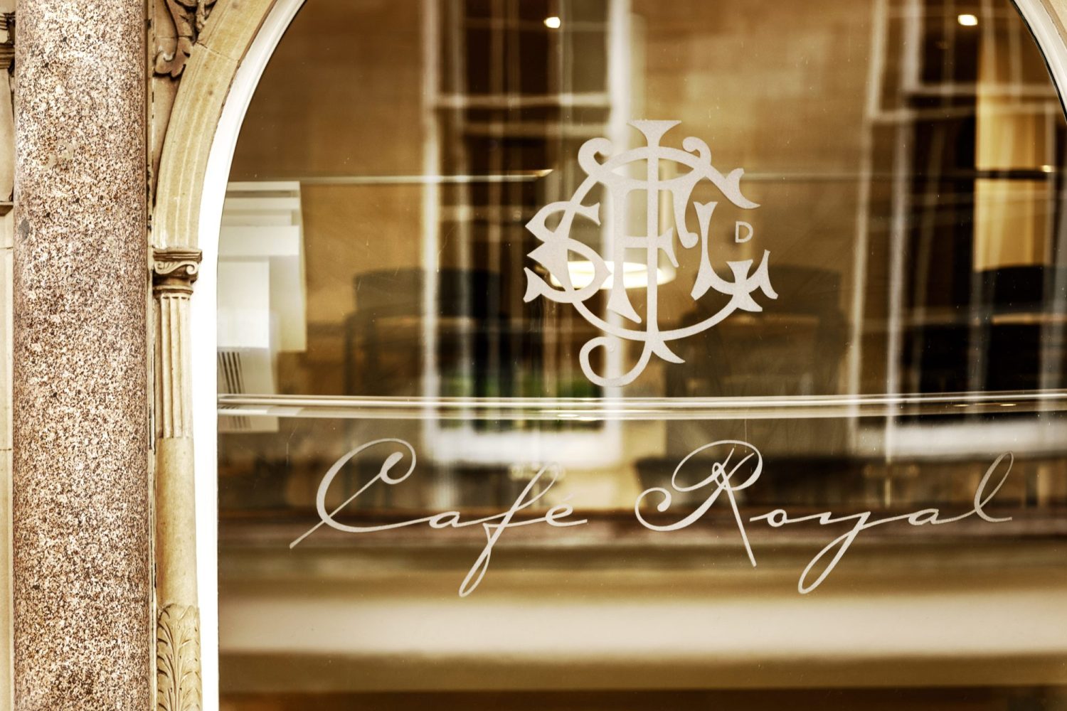 Window with stone arch detailing around and a Cafe Royal logo sticker in the centre
