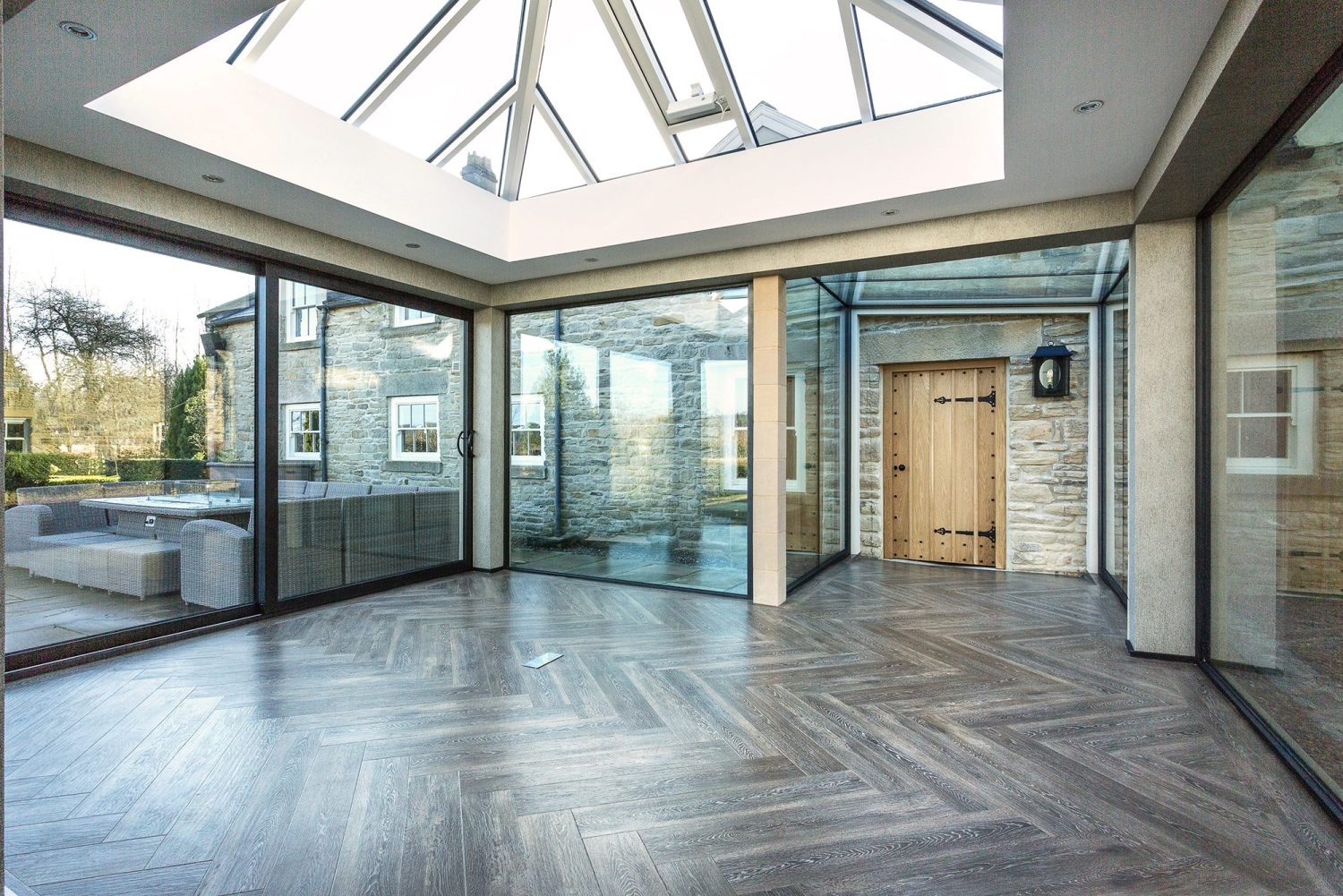 Interior of extension with glazed walls and ceiling and wooden flooring