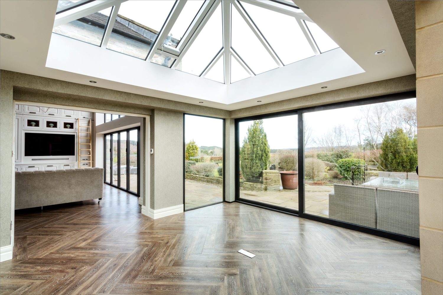 Extension with glazed walls and ceiling and wooden flooring through to living area
