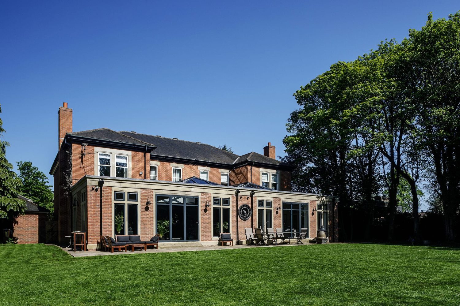 Exterior back of house with brick walls and black framed glazed doors to garden