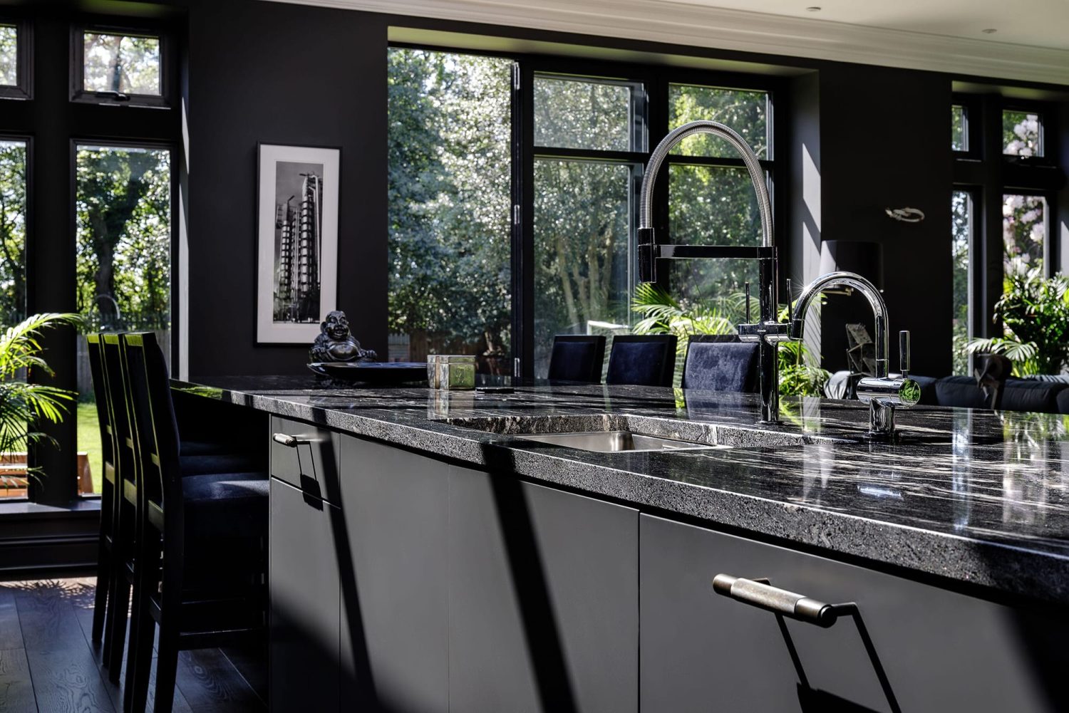 Dark grey kitchen island with dark marble countertop and sink built in with chrome taps