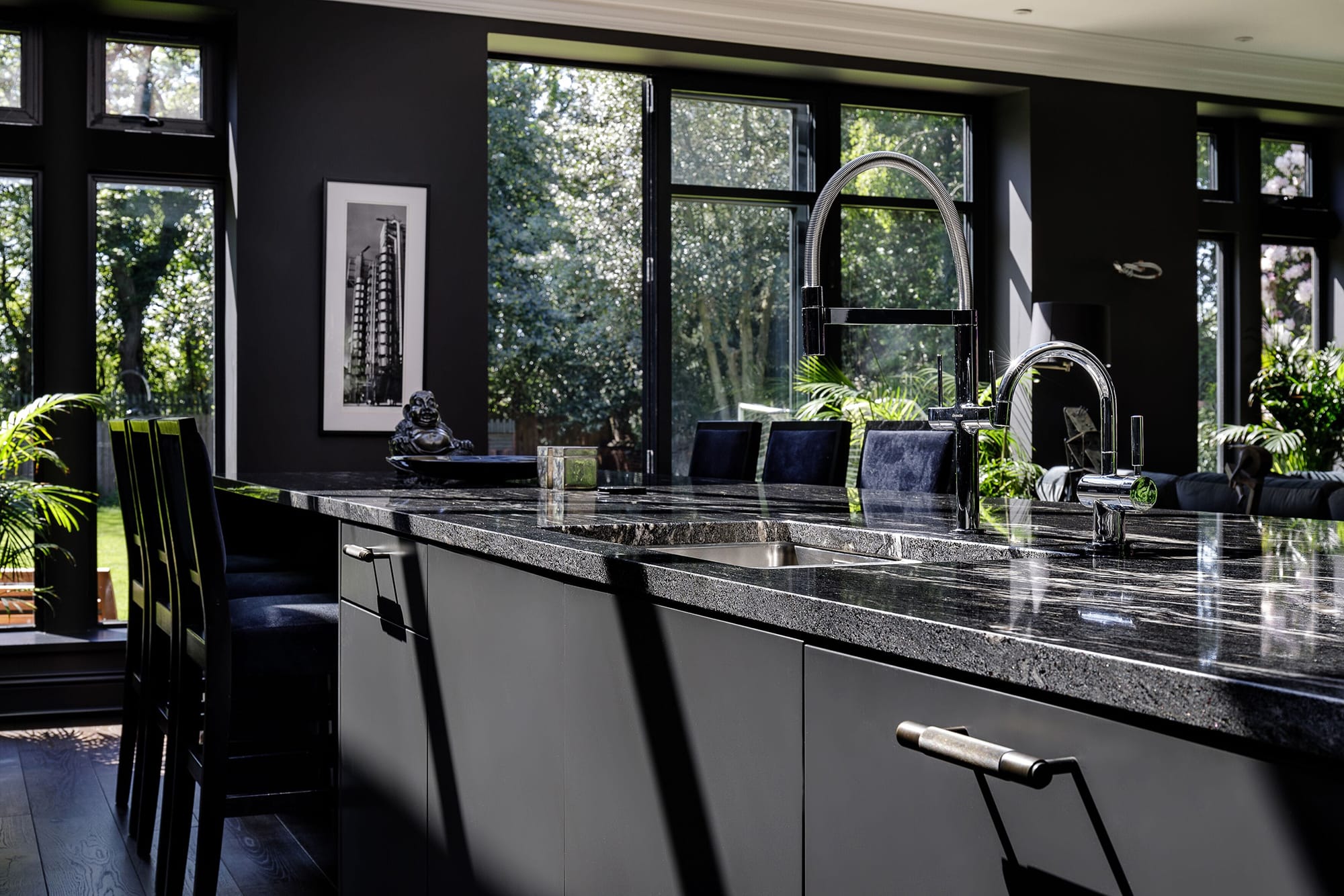 Dark grey kitchen island with dark marble countertop and sink built in with chrome taps