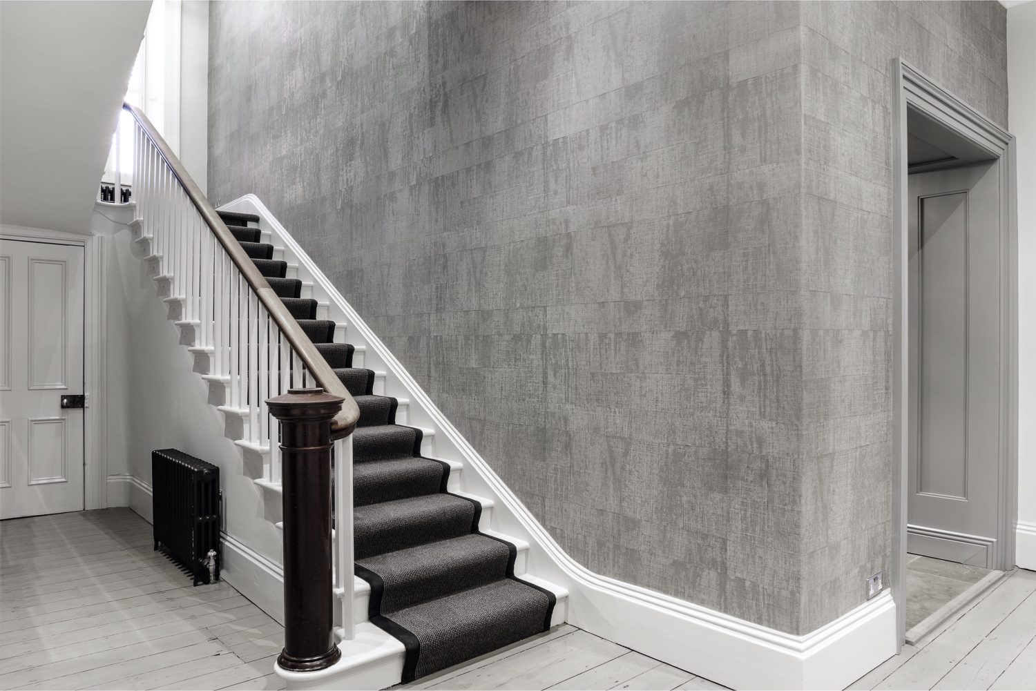 White staircase with dark grey stair runner and light grey wall with right