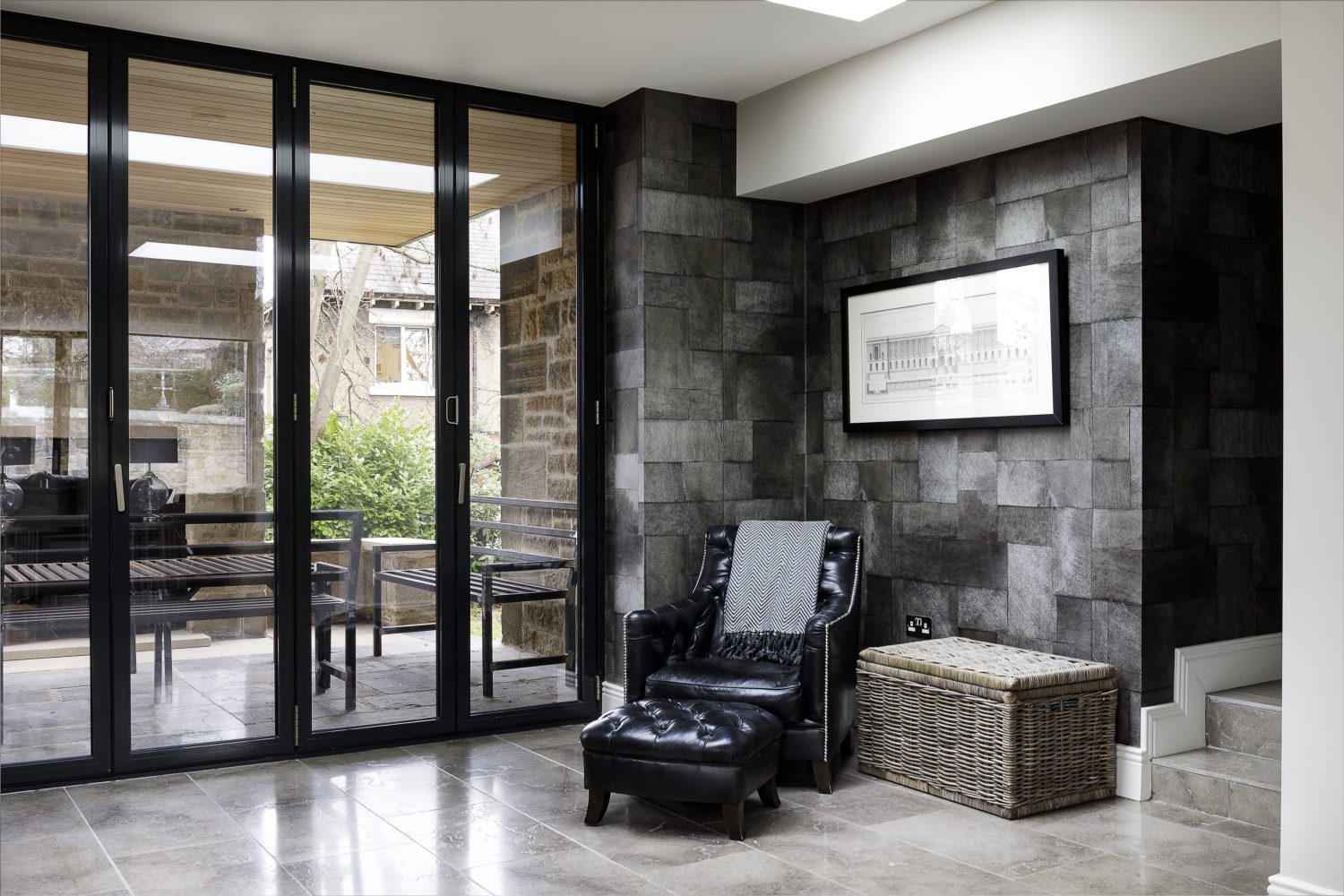 Black leather chair in corner with dark grey wall behind and glazed sliding doors to the left