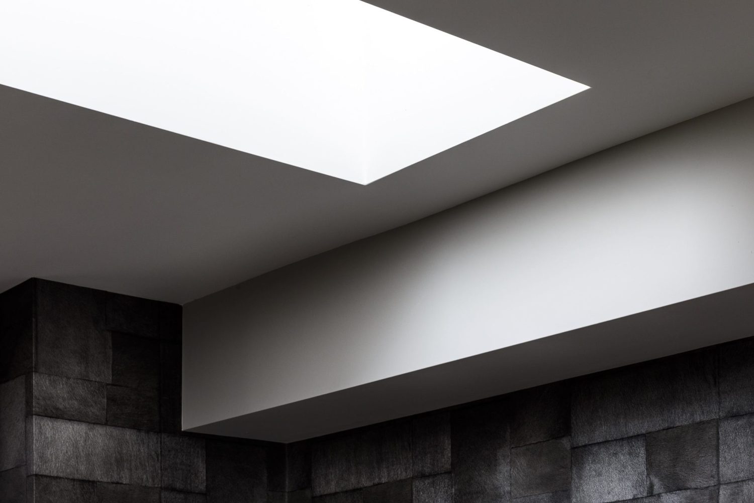 White ceiling with skylight and dark grey tiled walls below