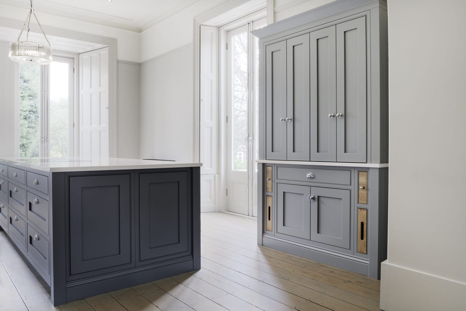 Kitchen with grey cabinets and island in the centre with white french double doors behind