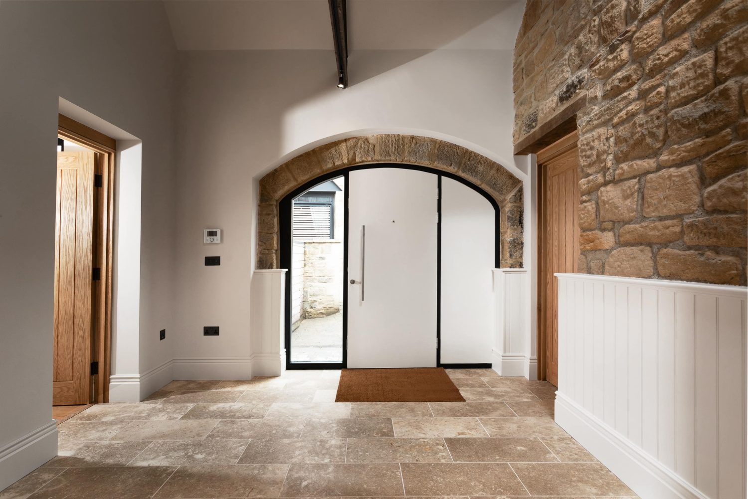 Arched white front door with exposed stone border and long silver handle