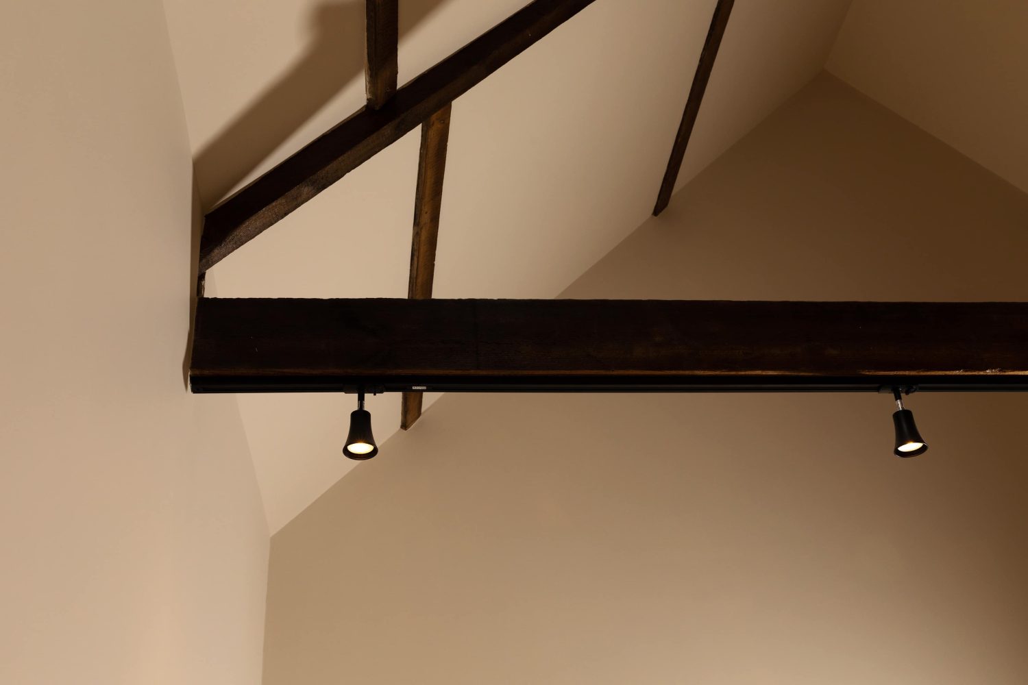 Wooden beam across ceiling with two small black lights hanging from the bottom