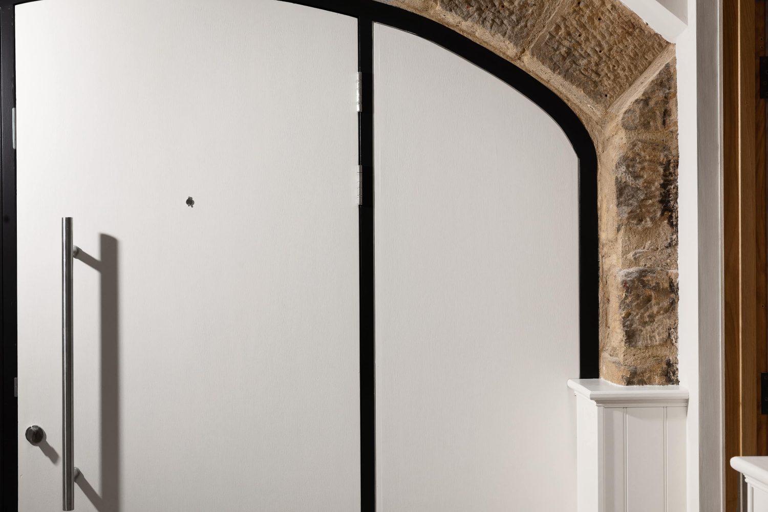 White door with long silver handle and exposed stone border