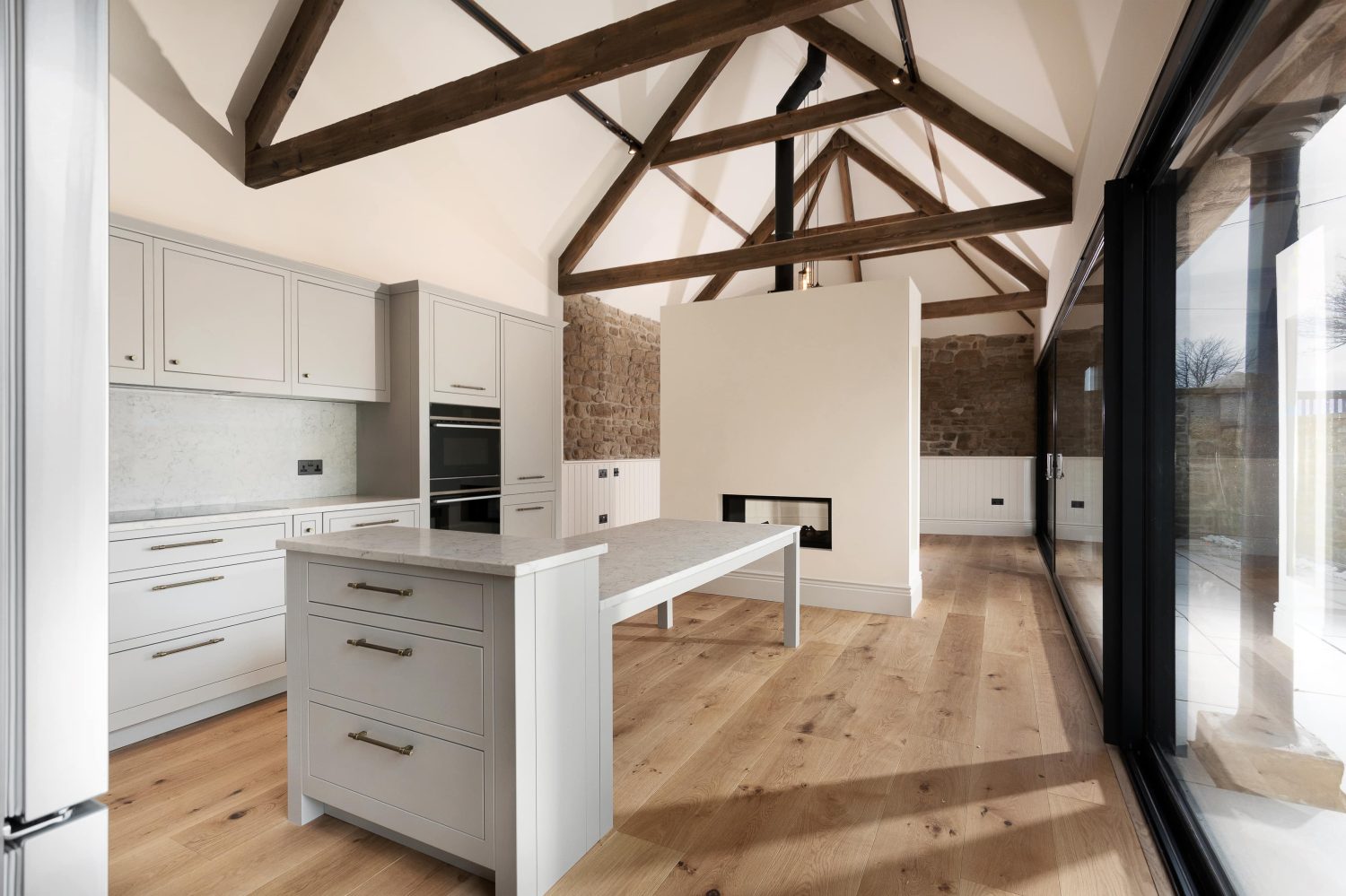 Kitchen with island next to media wall with fireplace within